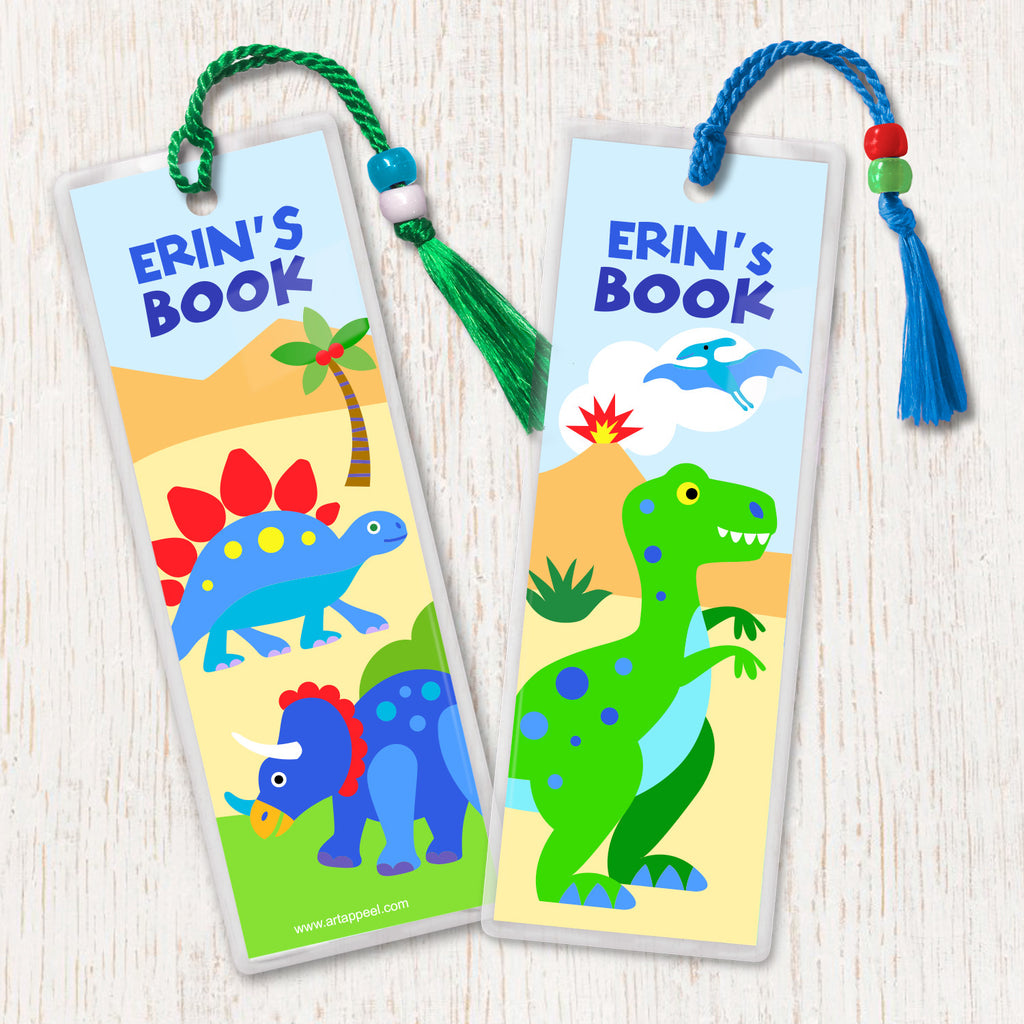 Kids personalized name bookmarks with dinosaurs in a prehistoric landscape, decorated with tassell and beads.