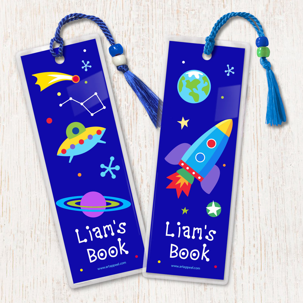 Space themed kids bookmarks with rocket ship, planets and stars on a dark blue background, decorated with tassell and beads.