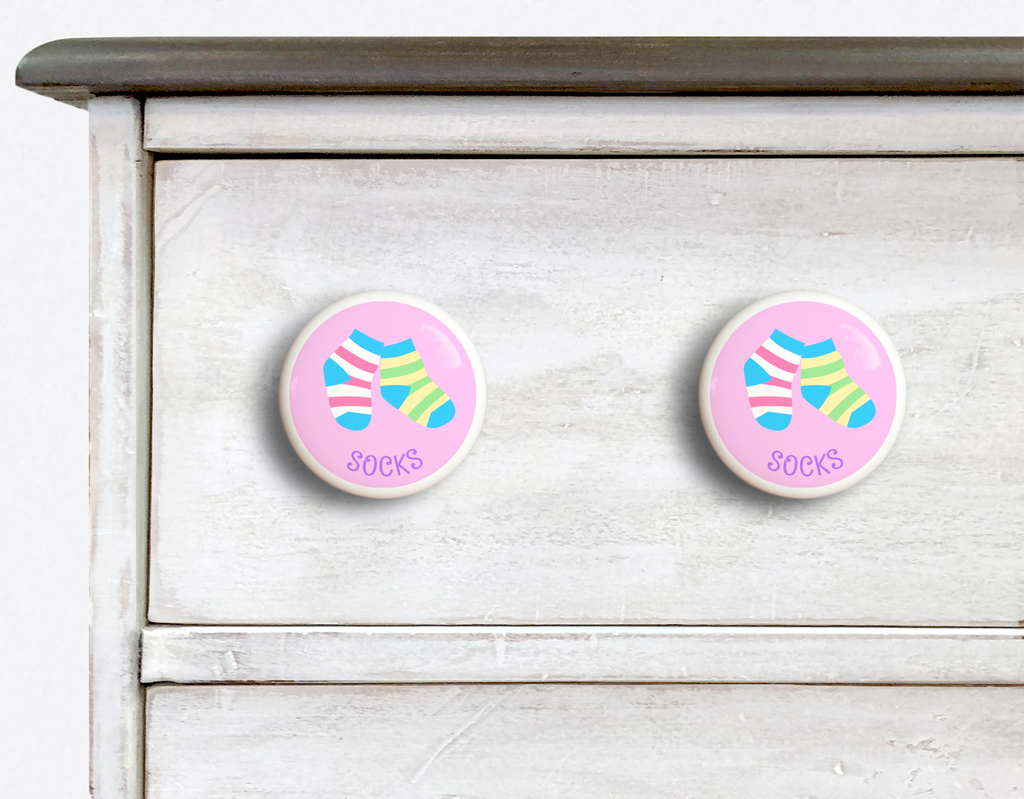 2 Ceramic drawer knobs on a dresser, striped socks on a pink ground with the word socks written below