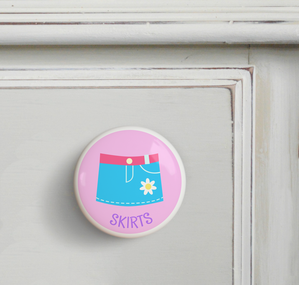 Ceramic drawer knob on a dresser with Girl's Skirt on a pink background with the word Skirts written below