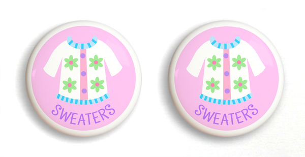2 Ceramic drawer knobs, girls sweater on a pink ground with the word Sweaters written below