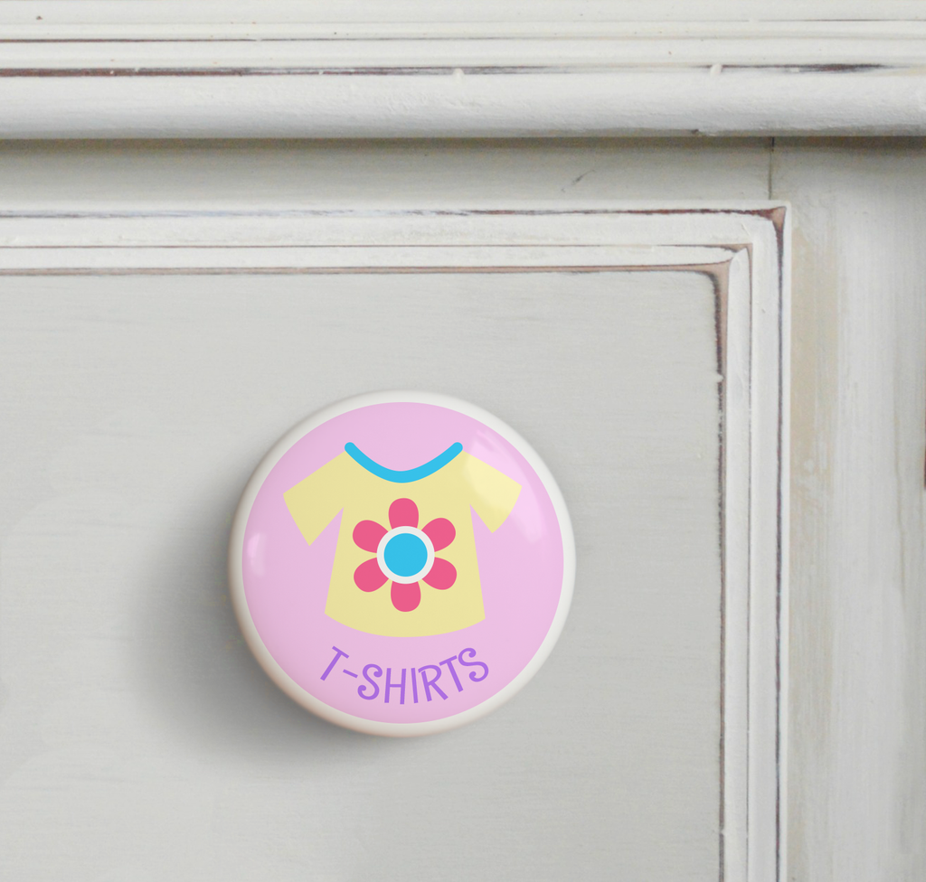 Ceramic drawer knob on a dresser, with a yellow girl's t-shirt on a pink background with the word T-Shirts written below