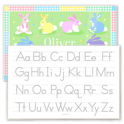 Kids placemat reverse side featuring a gray alphabet writing guide with uppercase and lowercase letters on lined handwriting practice rows, with pastel Easter bunny placemat design visible behind.