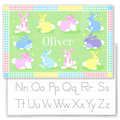Personalized kids placemat with colorful pastel Easter bunnies on a green background, gingham patchwork border, and the name Oliver in the center.