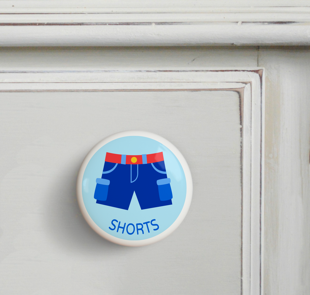Ceramic drawer knob on a dresser, with boy's shorts on a light blue ground with the word shorts written below