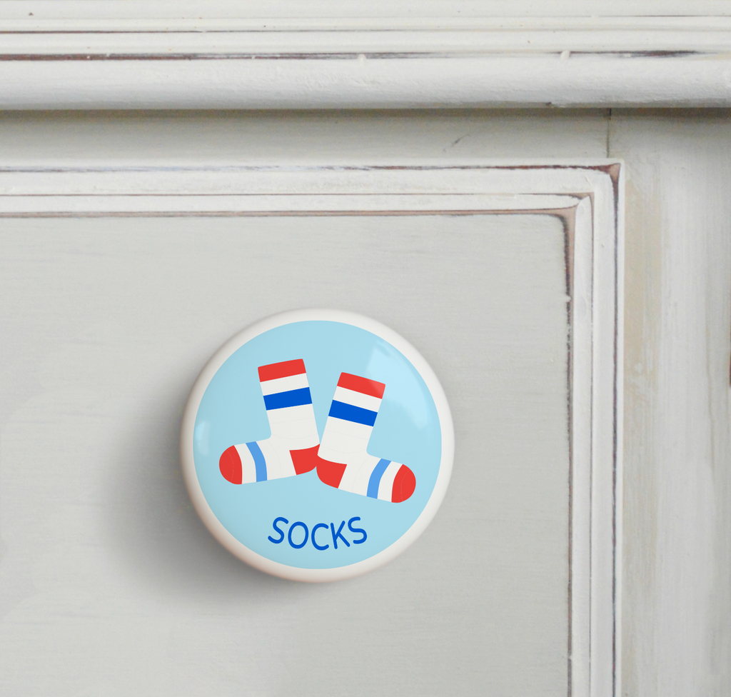 Ceramic drawer knob on a dresser, white socks with red and blue stripes on a light blue ground with the word socks written below