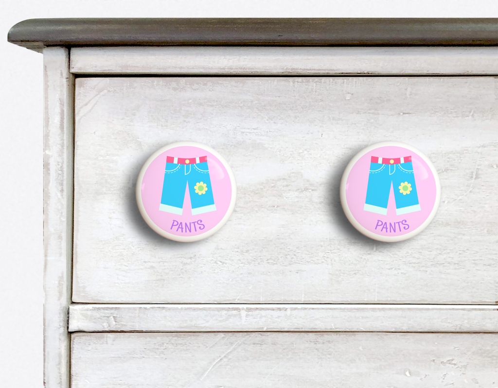 2 Ceramic drawer knobs on a dresser, girls pants on a pink ground with the word Pants written below