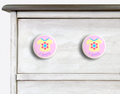 2 Ceramic drawer knobs on a dresser, girls t-shirt on a pink ground with the word T-Shirts written below