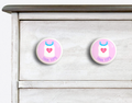2 Ceramic drawer knobs on a dresser, girls tank top on a pink ground with the word Tank Tops written below