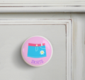Ceramic drawer knob on a dresser with Girl's Skirt on a pink background with the word Skirts written below