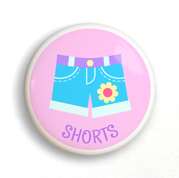 Ceramic drawer knob with girl's shorts on a pink background with the word Shorts written below