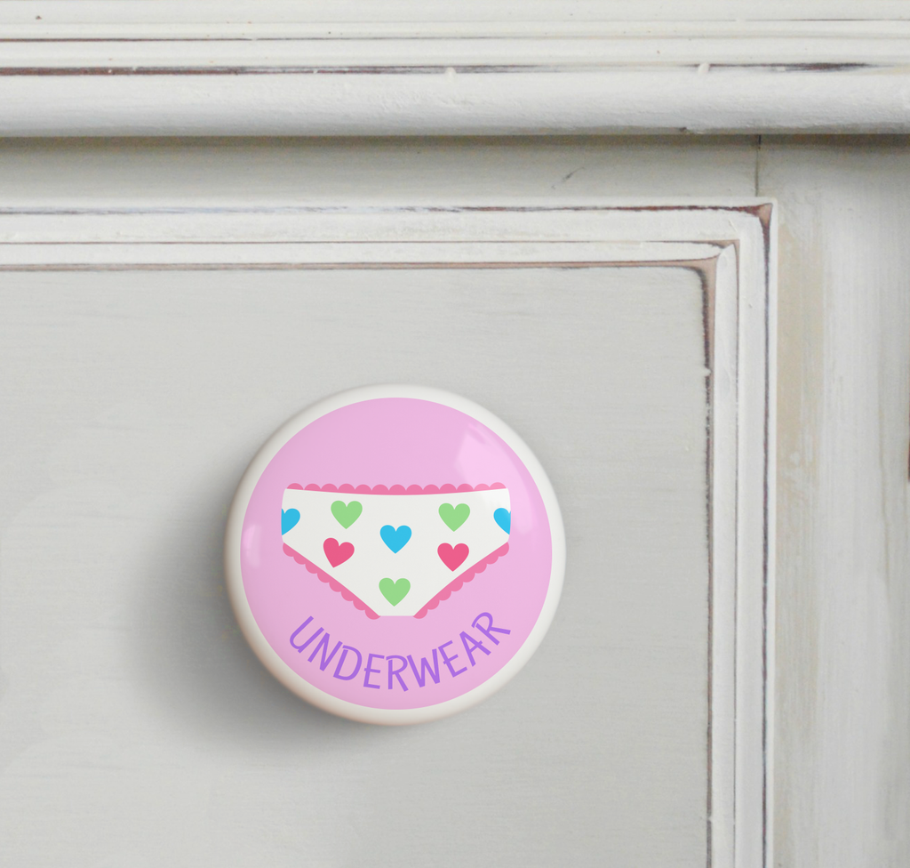 Ceramic drawer knob on a dresser, underwear on a pink background with the word ***s written below