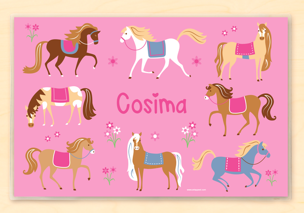 Toddler girls personalized laminated placemat with pink horses and ponies and flowers on a pink background with the child's name in hot pink in the center