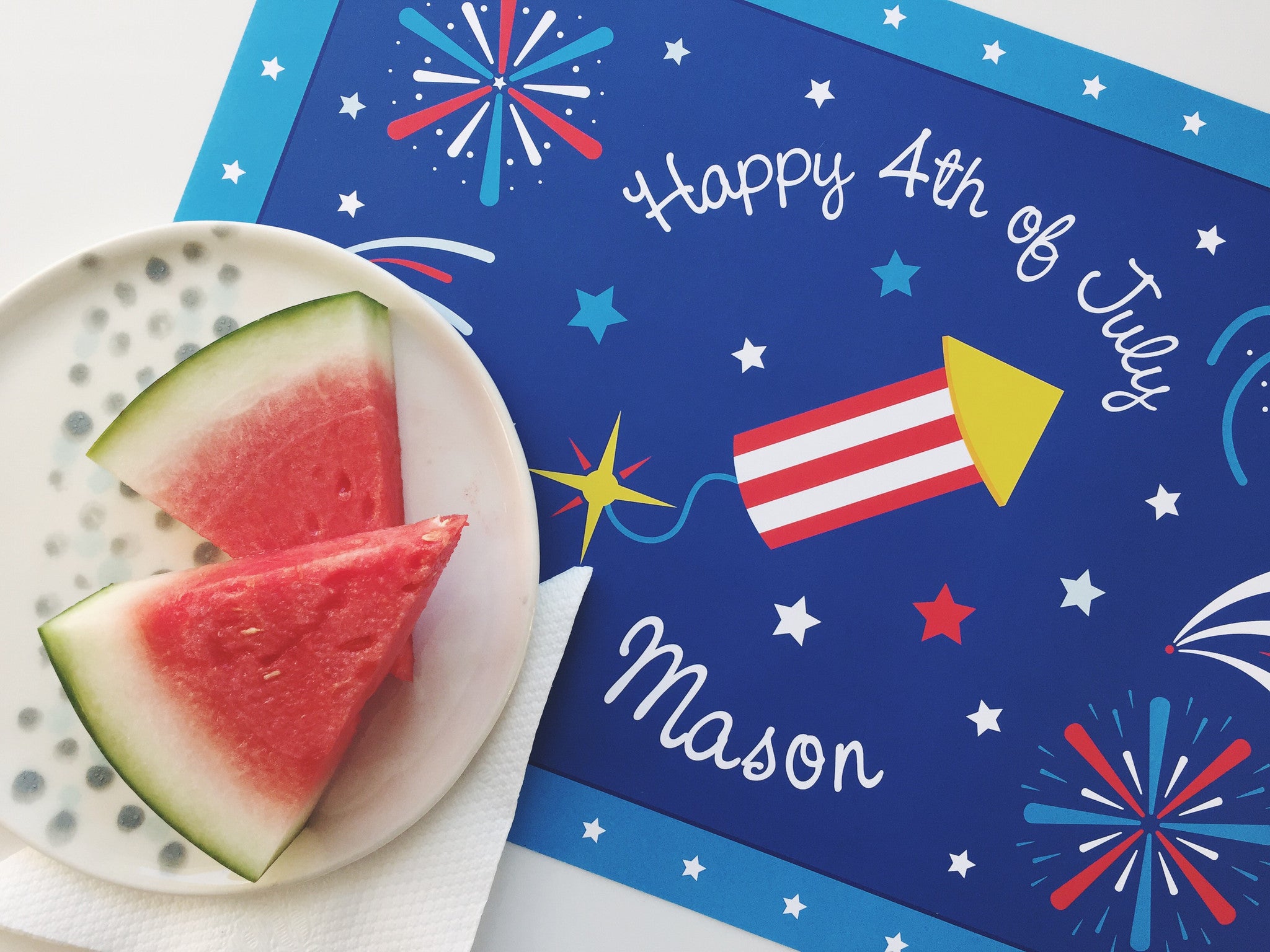 Happy 4th of July patriotic personalized kids placemat with a blue background, fireworks, firecracker, and watermelon slices