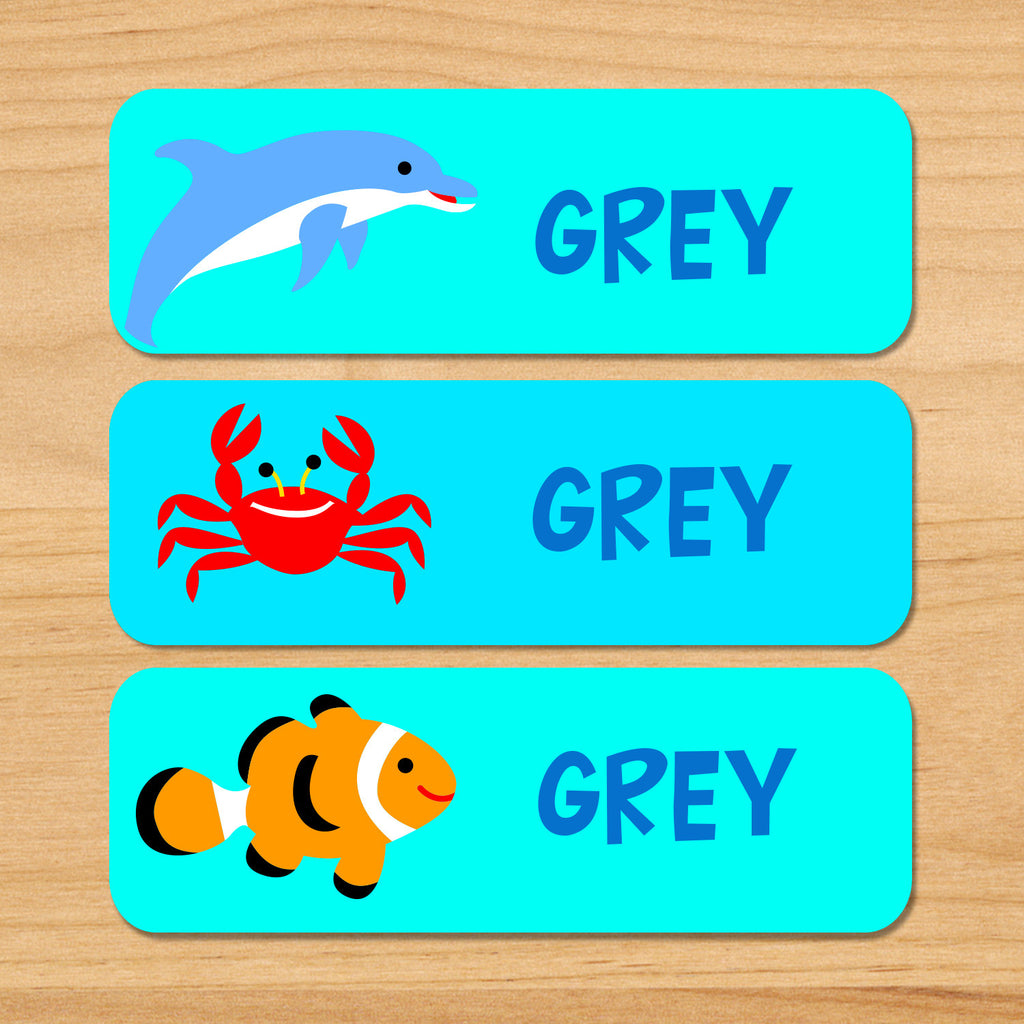 Ocean personalized kids waterproof labels with name, dolphin, crab, and clownfish on blue ocean water background