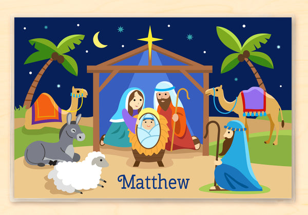Kids personalized placemat with illustration of Nativity scene with manger, Mary Joseph and Baby Jesus, palm trees, shepherd, animals and the Christmas star.  Personalized with childs name at the bottom.