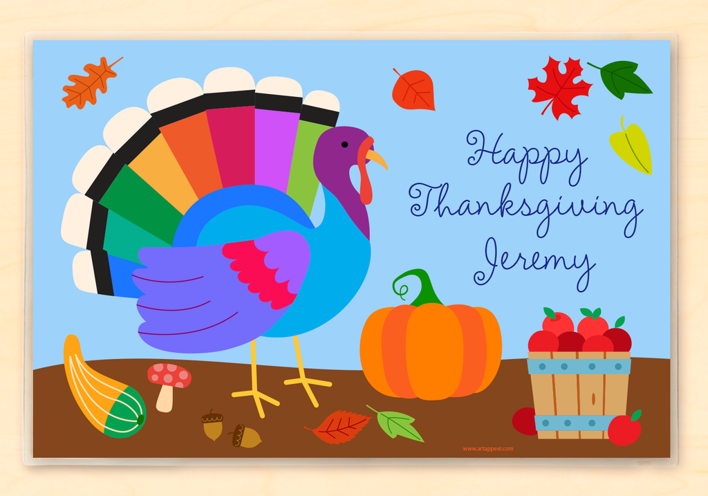 Thanksgiving placemat features a colorful turkey, pumpkin and basket of apples on a blue background. Personalized with child's name